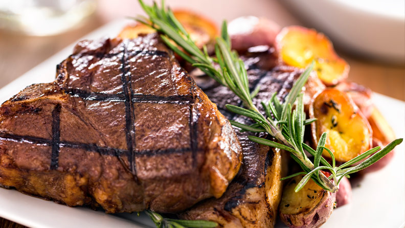 t-bone steak with potatoes and garnish